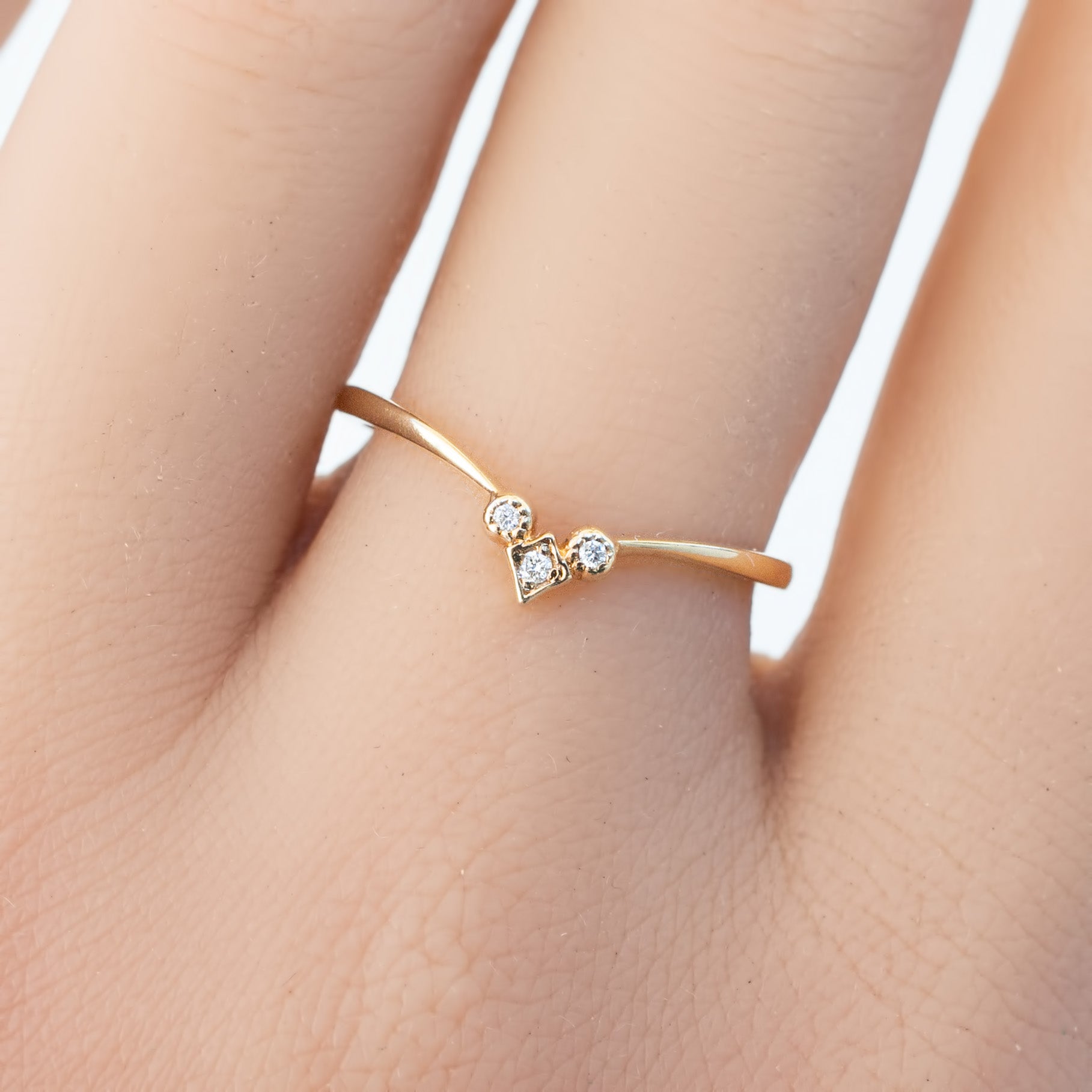 Delicate solid gold star accent ring with natural white diamonds on a slender band worn on finger