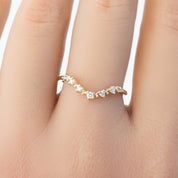 Close-up of a solid gold Norah Tiara Ring with natural white diamonds in a curved V-shape on a finger