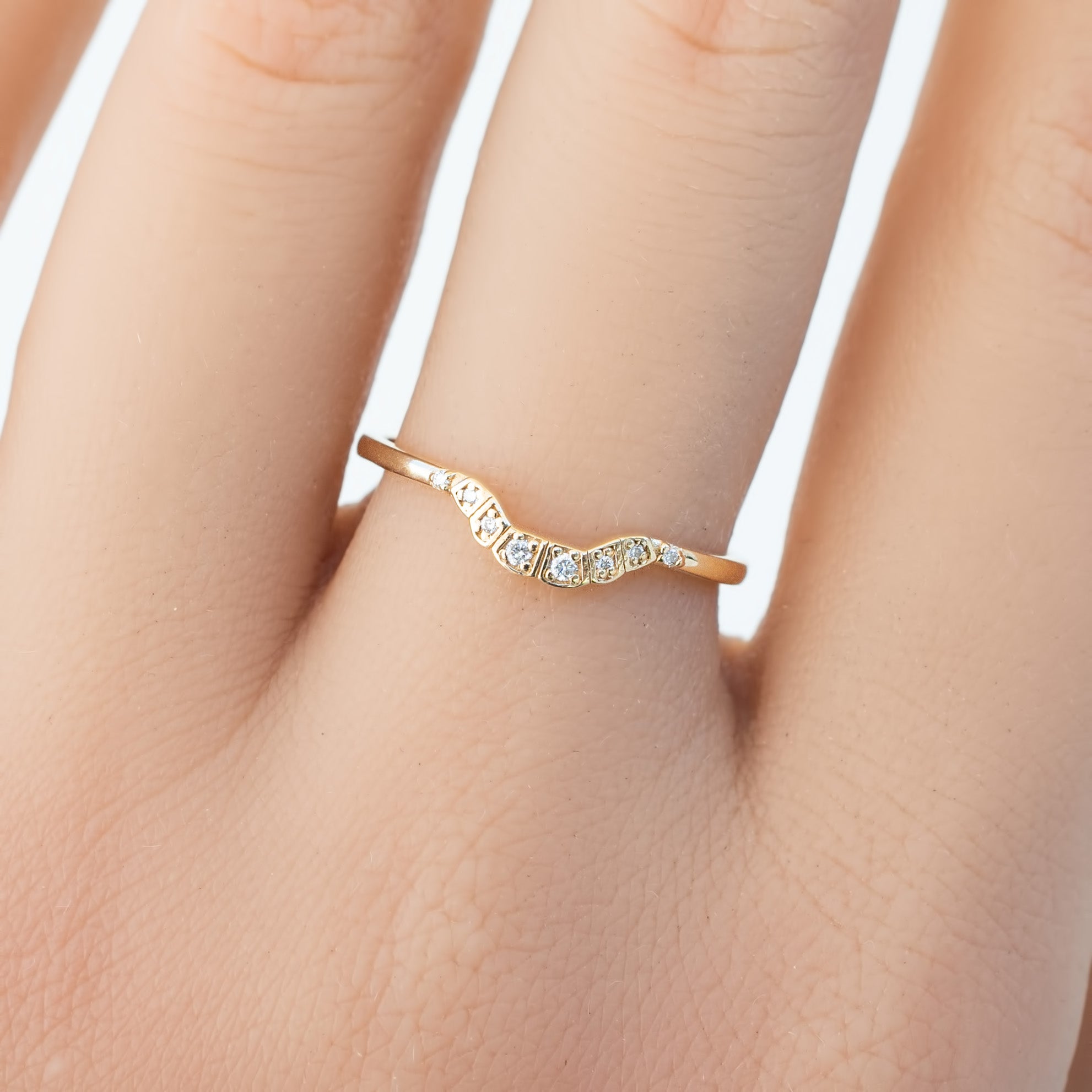 Isabel's curved solid gold ring with natural white diamonds on finger, delicate U-shaped band design