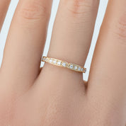 Close-up of a hand wearing a gold Eva ring with natural white diamonds in a half-eternity style band