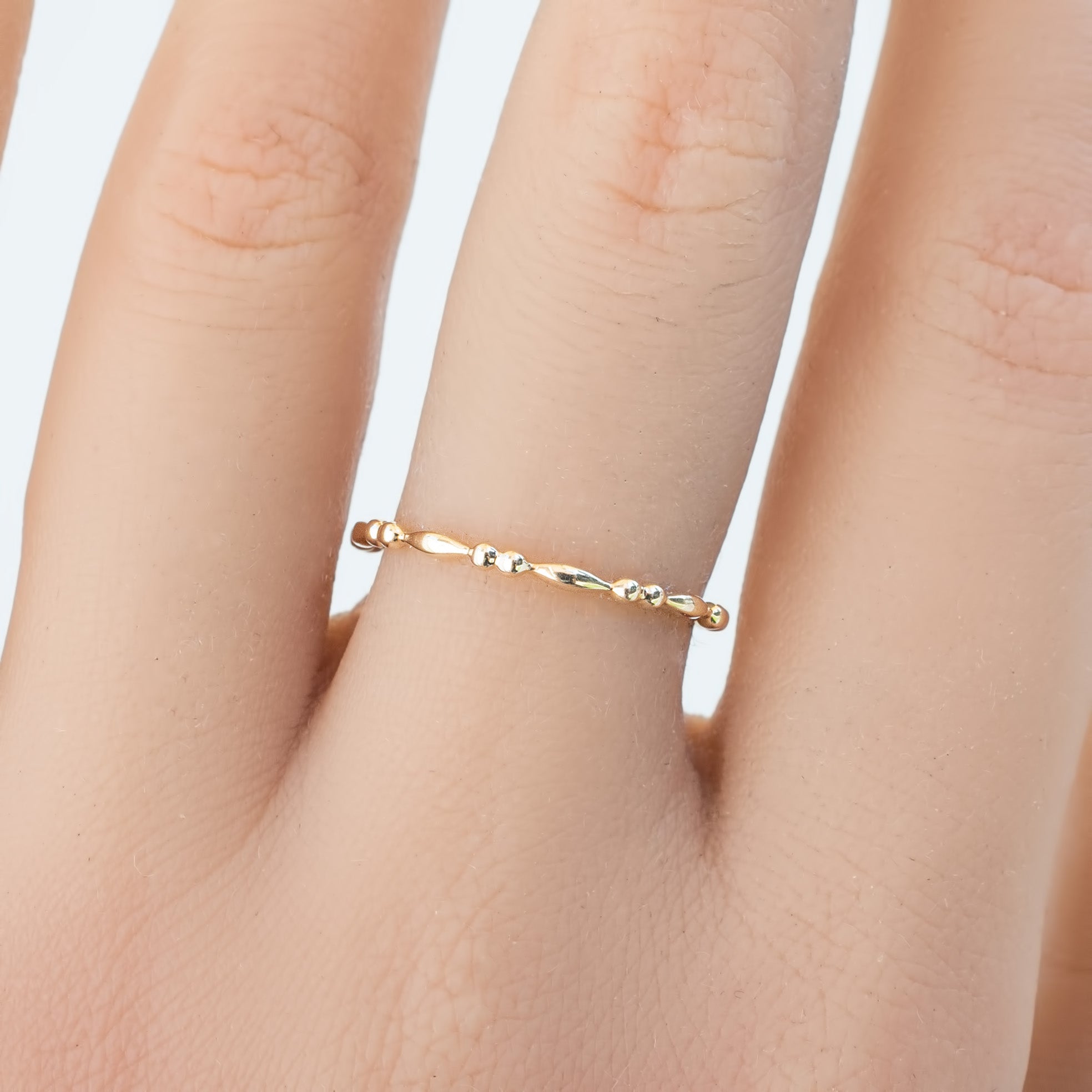 Delicate 1.5mm solid gold Adina full eternity bead ring on finger in recyclable kraft box packaging