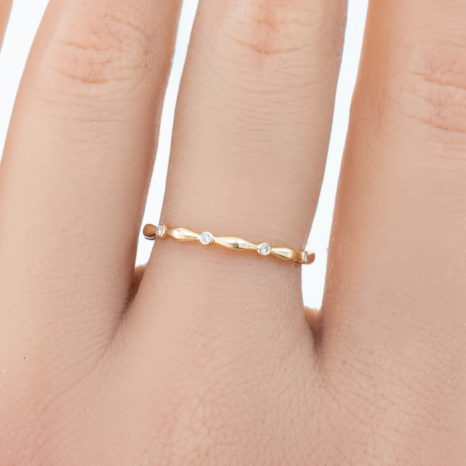 Delicate Aria Eternity Ring in solid gold with small natural white diamonds in a full-eternity design on a finger.