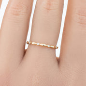 Delicate Aria Eternity Ring in solid gold with small natural white diamonds in a full-eternity design on a finger.