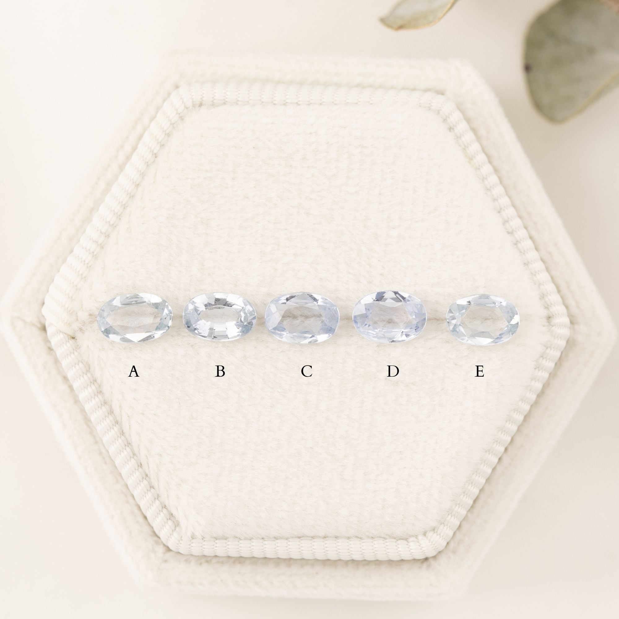 Three 'Estel Rings' with oval-shaped sapphires, in settings of 14k rose gold, 14k white gold, and 14k yellow gold, displayed against a light background., oval shape gemstone