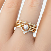 Stacked six star ring set featuring natural white diamonds in solid gold on a hand with smooth skin background.