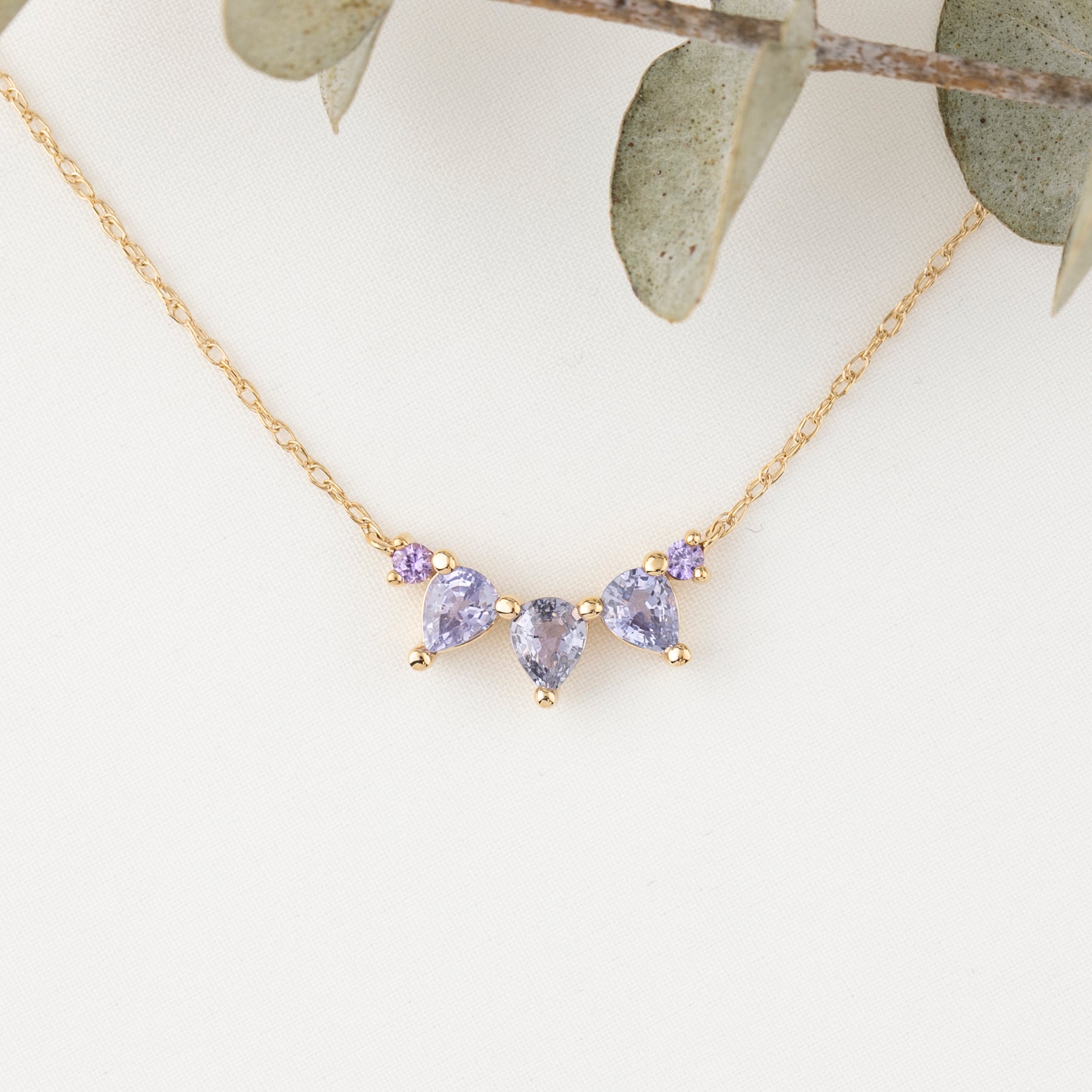 Gold necklace with purple gemstones on a white background