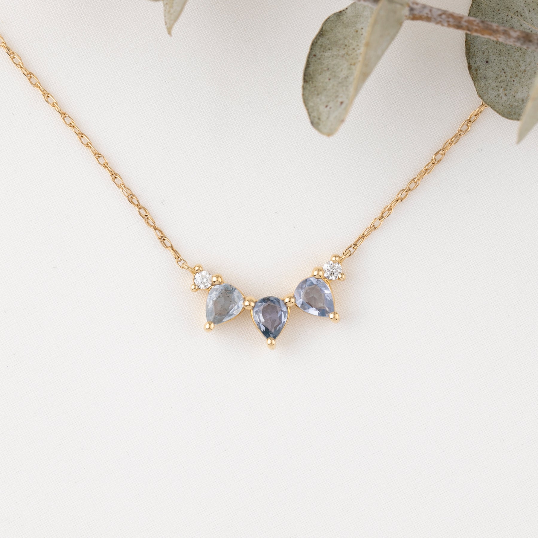 Gold necklace with three teardrop-shaped gemstones on a light background