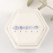 A series of round blue sapphires, set in a row, displayed in a hexagonal white box with each labeled A to E.