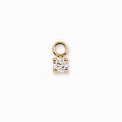 Gold charm with a clear gemstone on a white background