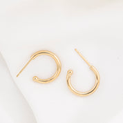 Gold hoop earring with measurements of appx 13.5mm diameter on a white background