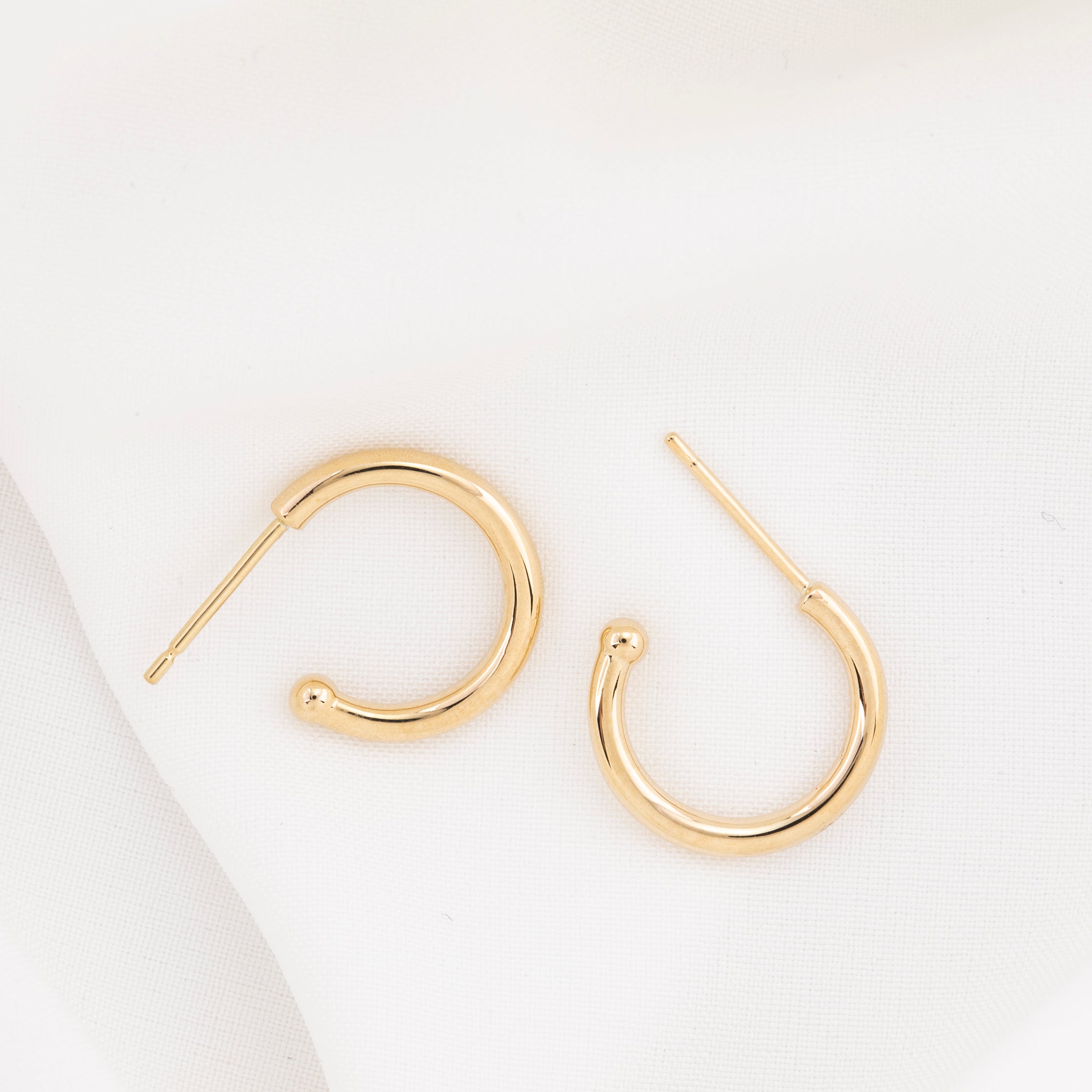 Gold hoop earring with measurements of appx 13.5mm diameter on a white background