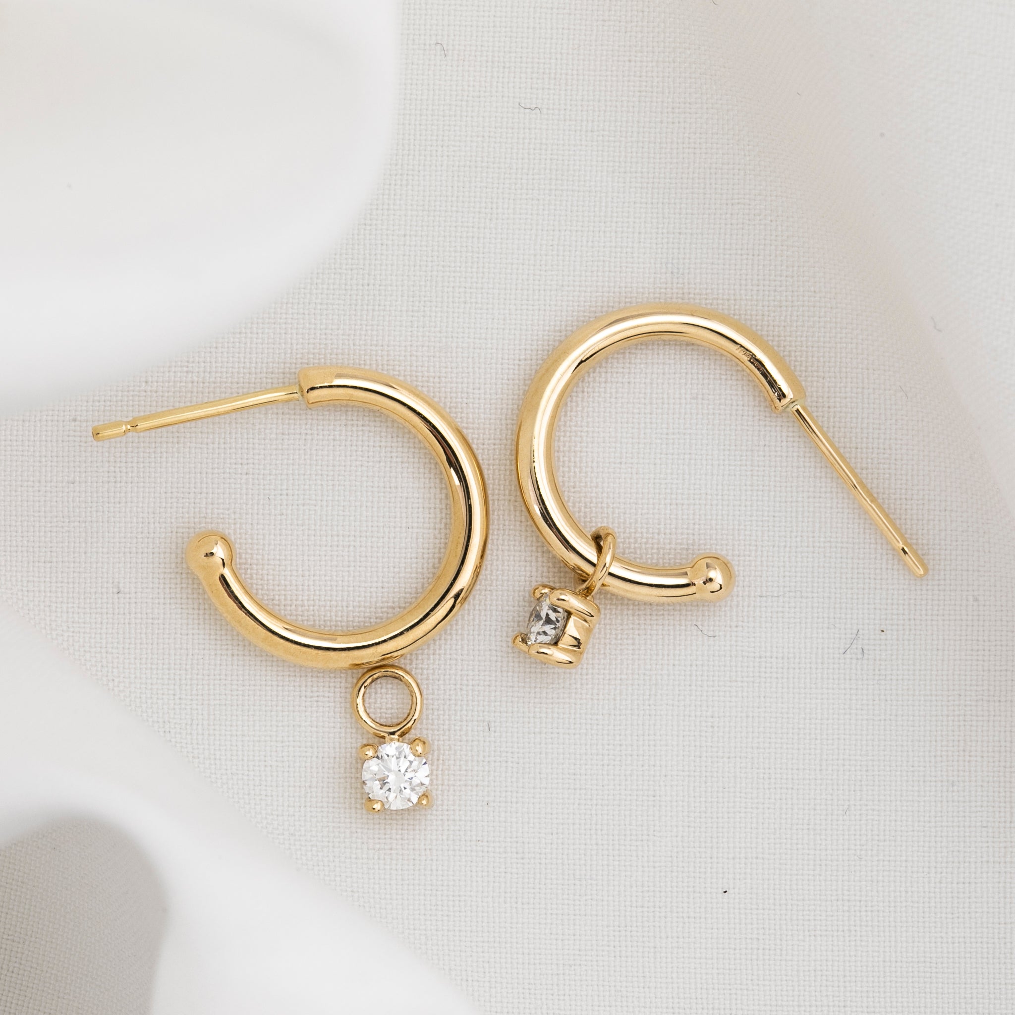 Gold hoop earring with measurements of appx 13.5mm diameter on a white background