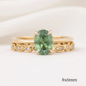 Gold ring with 8x6mm green gemstone and white diamonds set in an intricate detailed band design