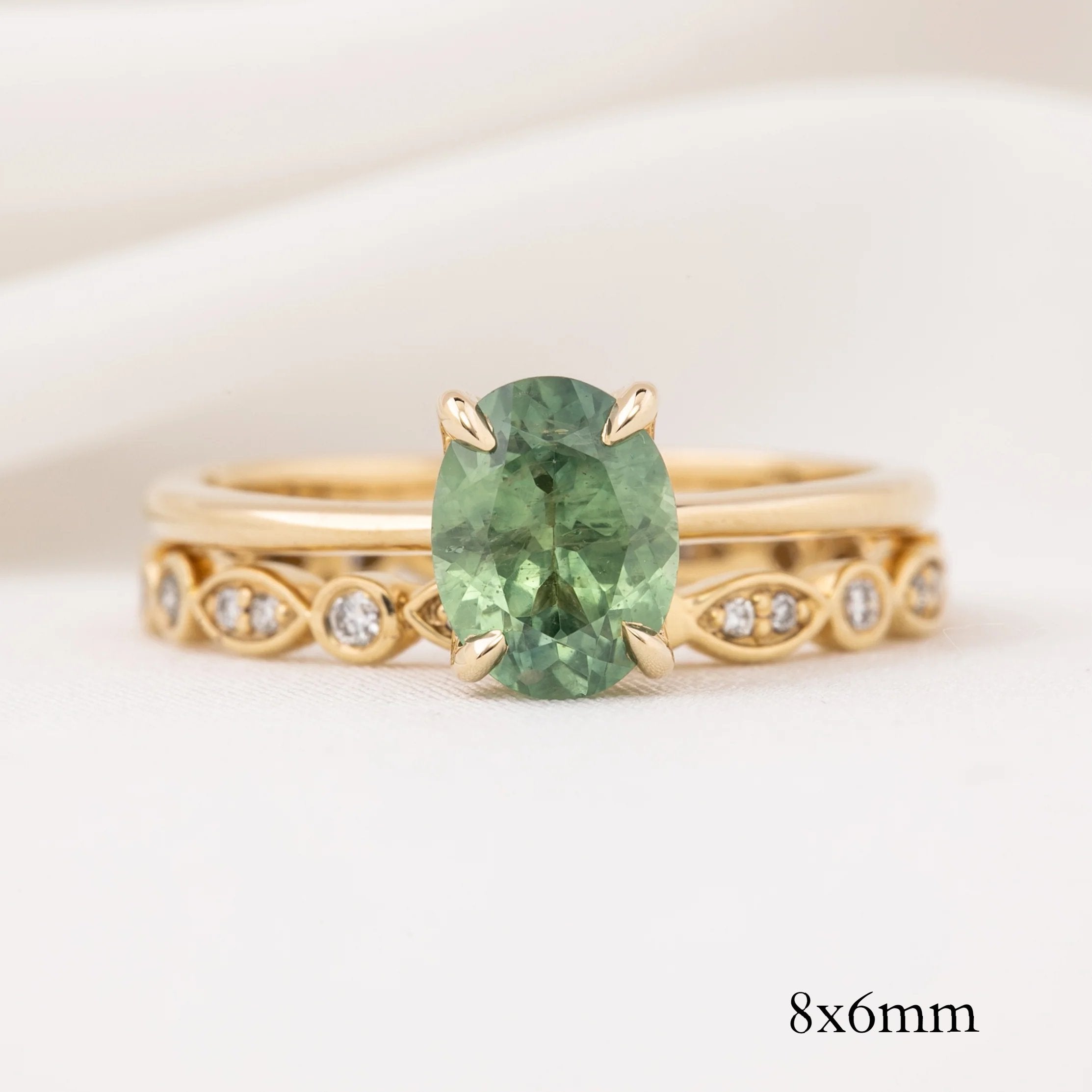 Gold ring with 8x6mm green gemstone and white diamonds set in an intricate detailed band design