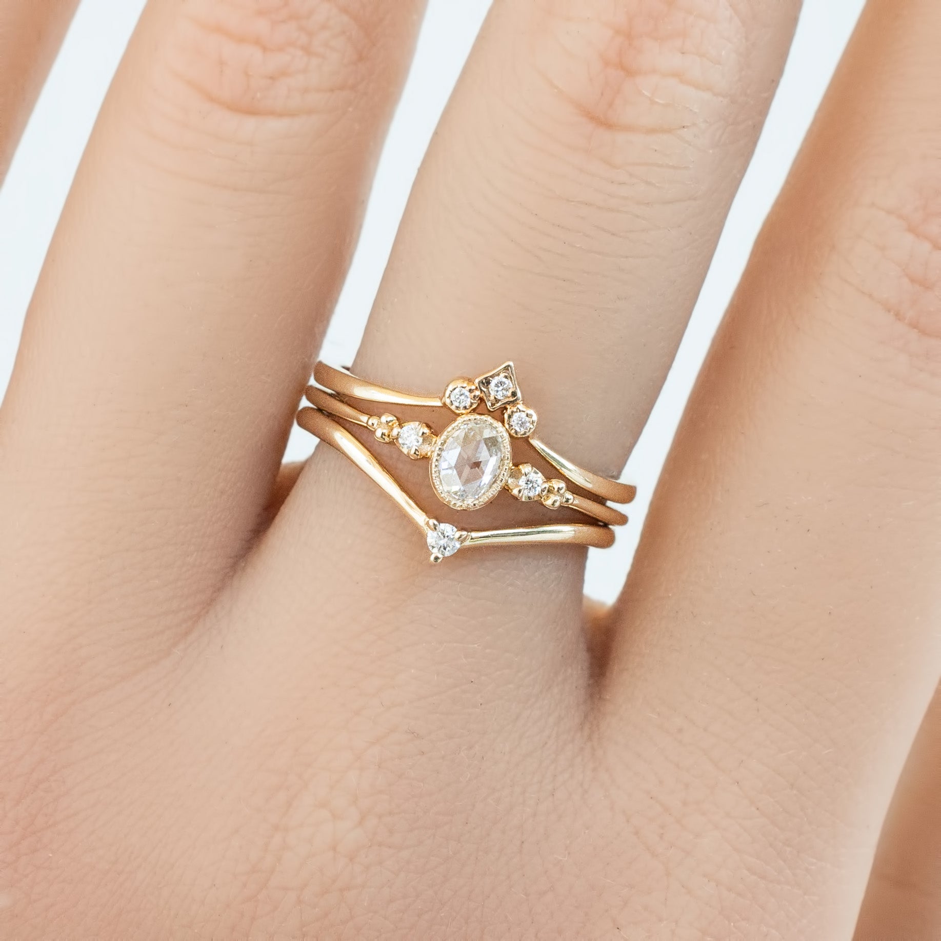 Hand wearing a solid gold star accent ring with natural white diamonds in recyclable kraft ivory box background
