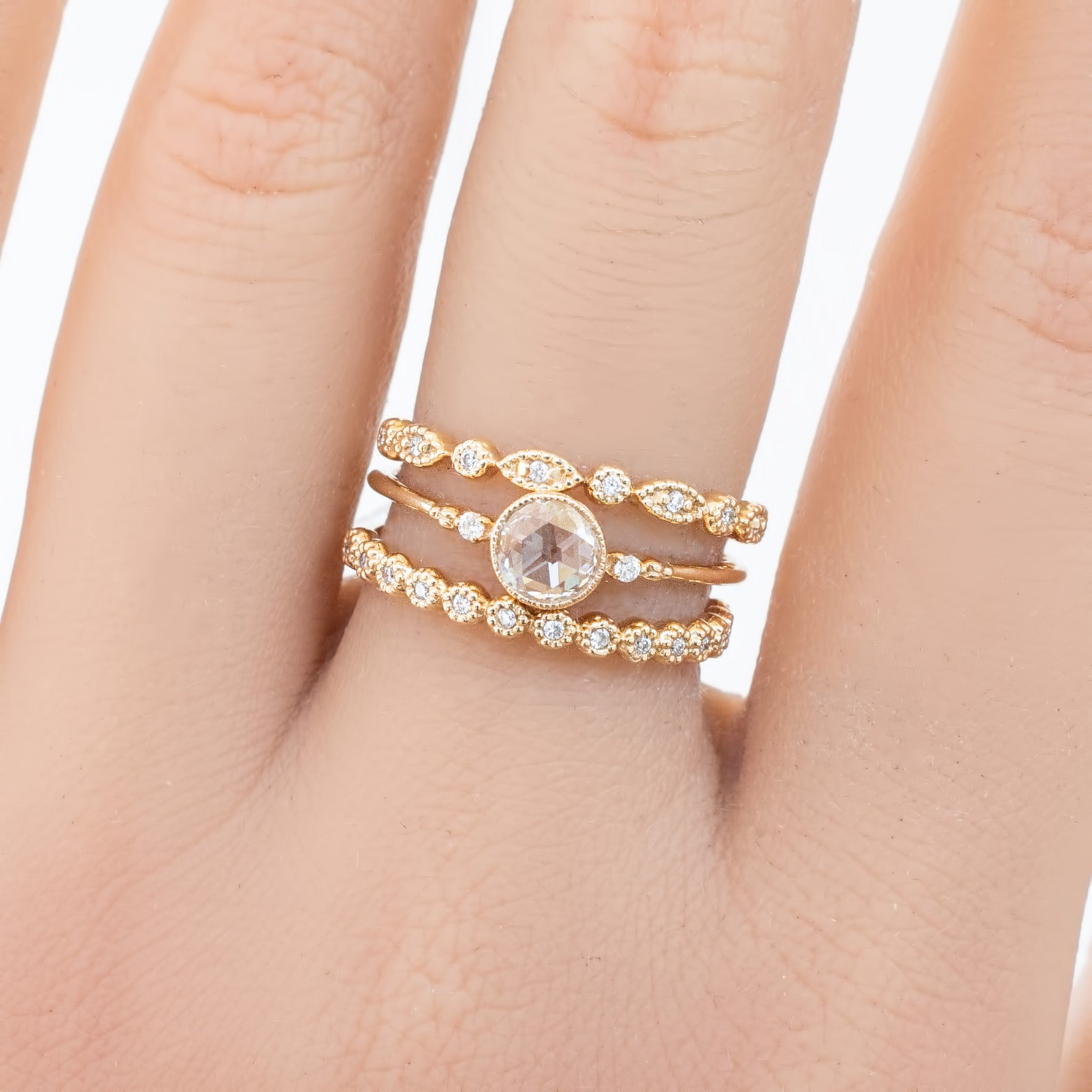 Gold eternity ring with natural white diamonds and intricate milgrain design on finger close-up