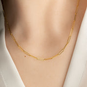 14k yellow gold paper clip chain necklace on a person wearing a white shirt