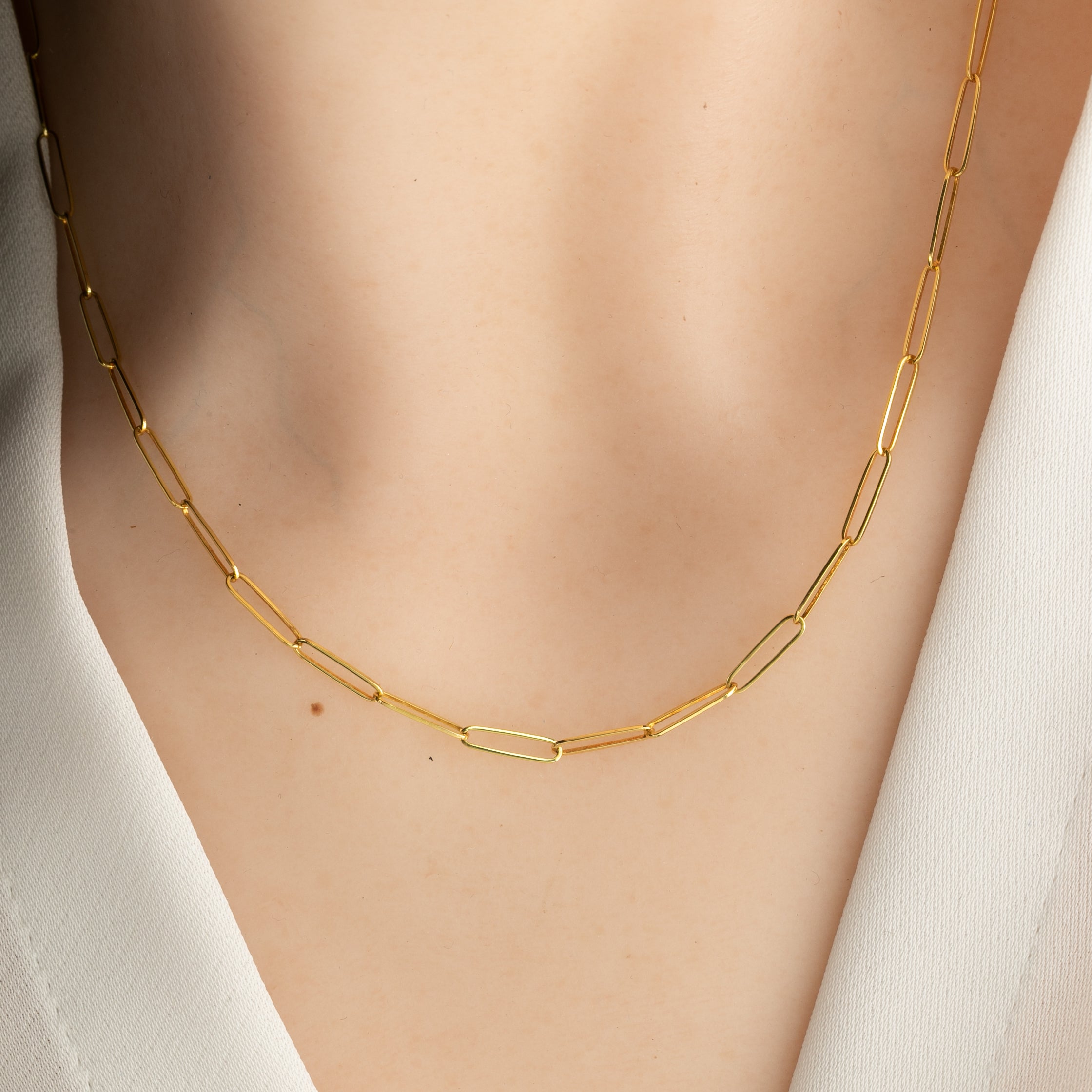 14k yellow gold paper clip chain necklace on a person wearing a white shirt