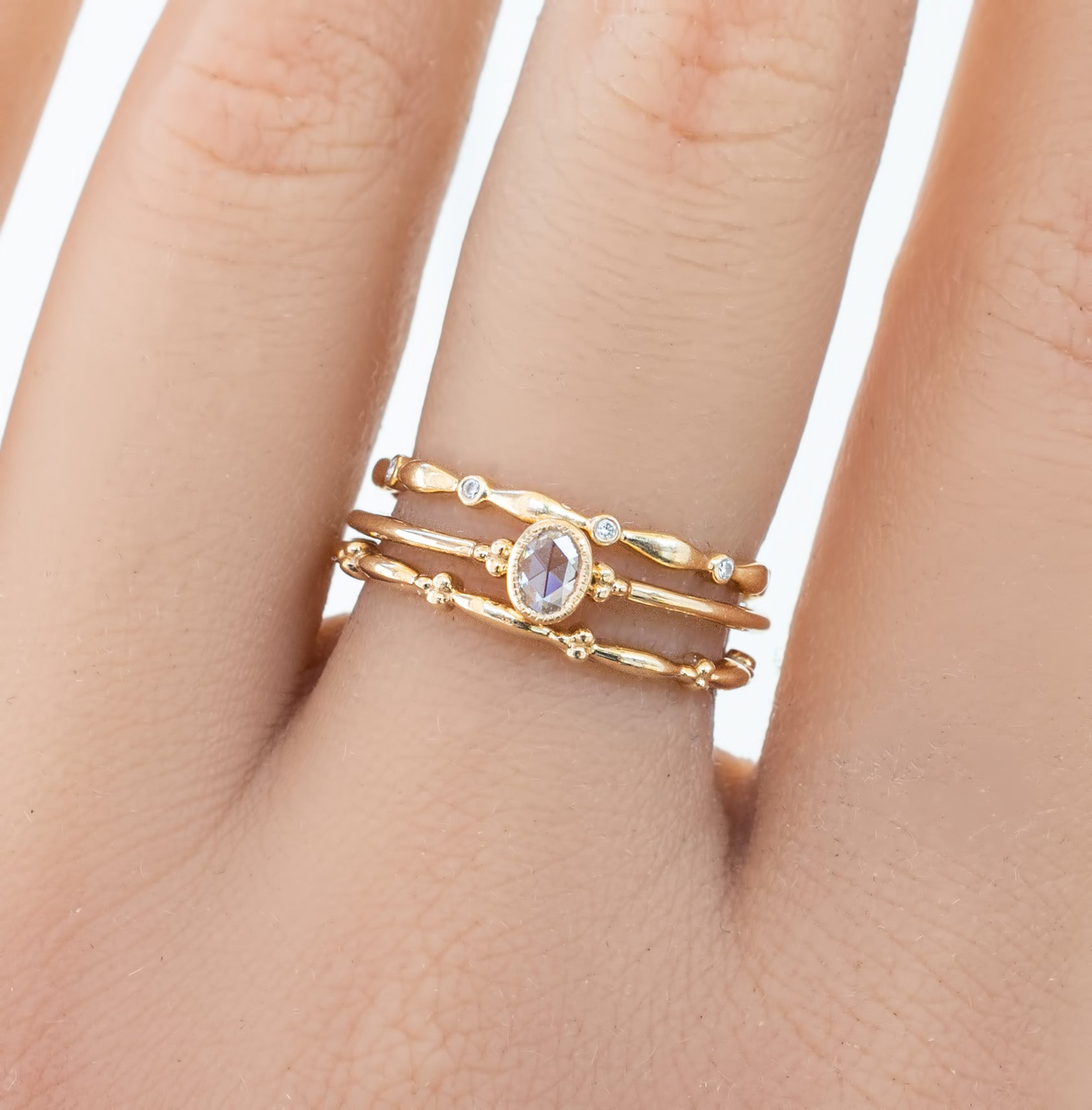 Hand wearing three delicate gold eternity rings with small natural white diamonds in full-eternity style