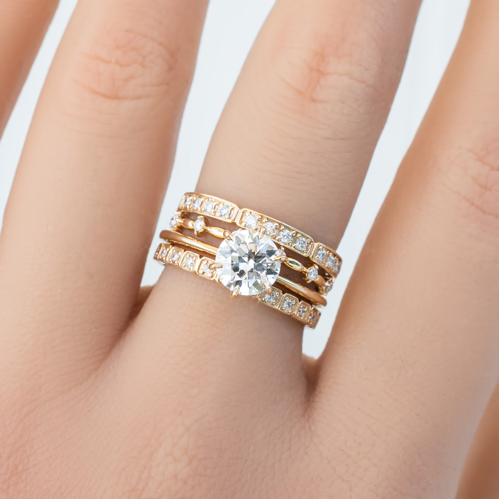 Hand wearing Eva Ring with natural white diamonds set in solid gold, featuring a sparkling centerpiece diamond