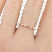Close-up of a hand wearing a delicate full eternity style gold bead ring with a 1.5mm band width.