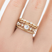 Close-up of hand wearing three gold rings with white diamonds in various shapes and settings