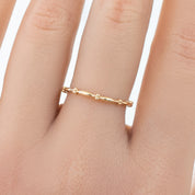 Close-up of a delicate 1.7mm Julia Ring in solid gold with a beaded eternity design worn on a finger