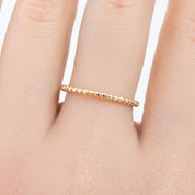 Close-up of a hand wearing a solid gold bead eternity ring with a 1.5mm band width on a finger