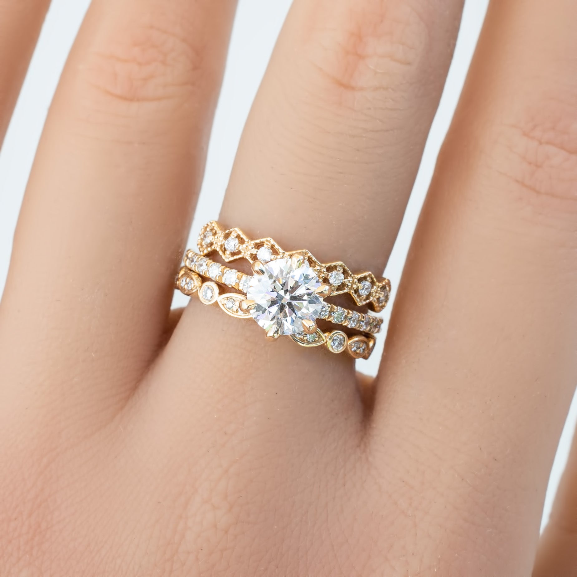Close-up of a hand wearing a gold Seren Ring with sparkling natural white diamonds and delicate band details