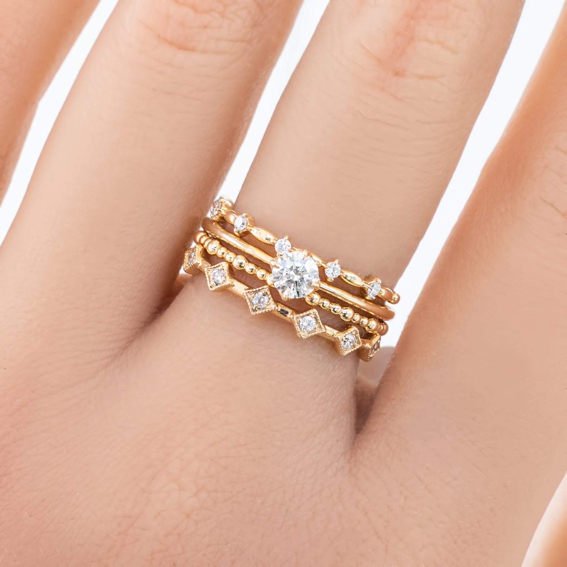 Hand wearing three delicate gold rings, including a full eternity bead style ring with diamonds on a 1.5mm band