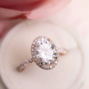 Close-up of a 3ct Neo Moissanite halo ring with French cut down setting on a soft pink background