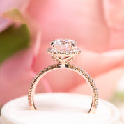3ct Neo Moissanite halo ring with half-eternity diamond band and unique flower-shaped base craftsmanship on pink background.
