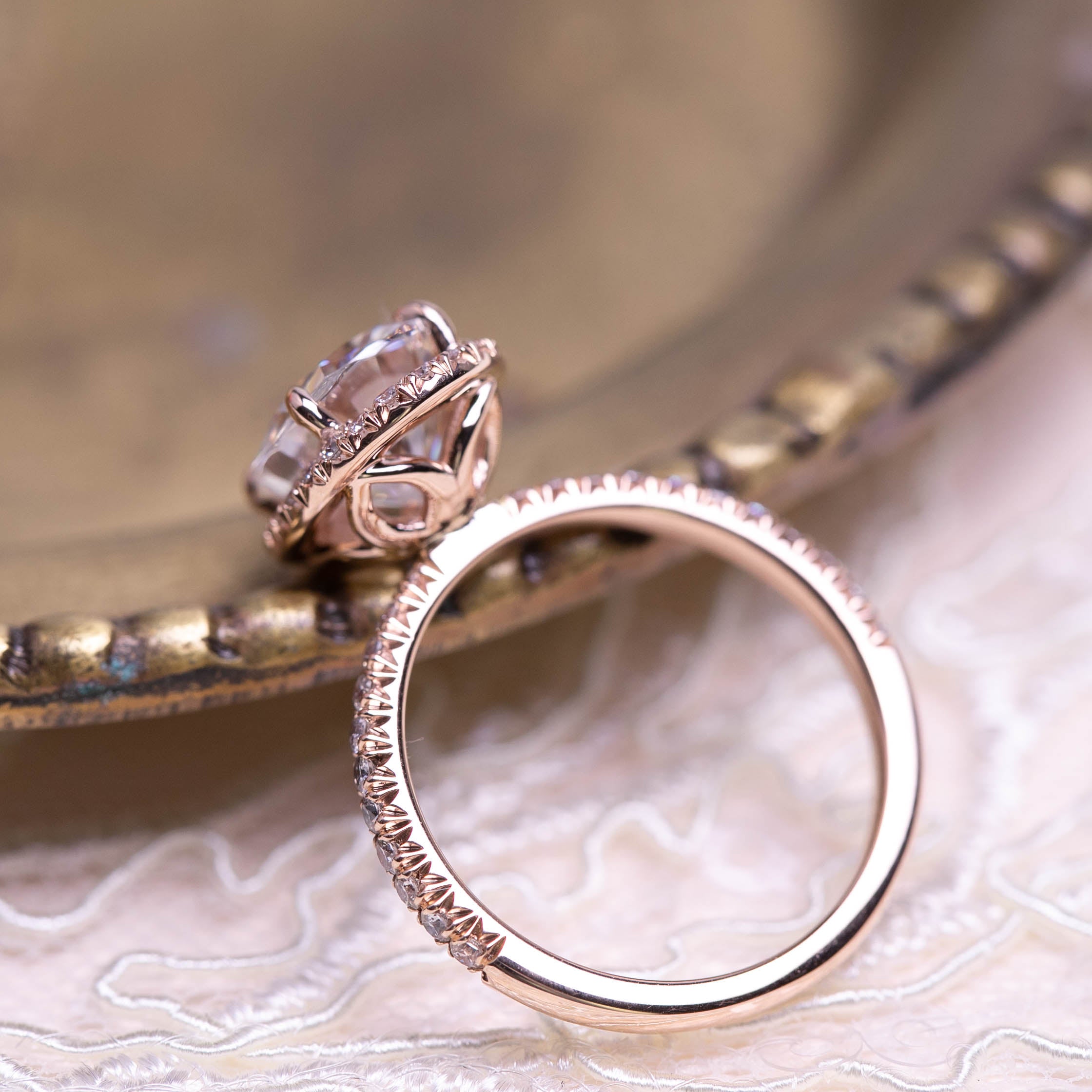 Close-up of a rose gold Neo Moissanite halo ring with 3ct center stone and half-eternity French cut down band