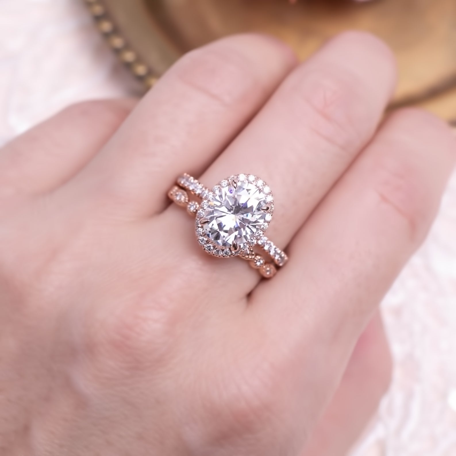 Hand wearing Neo Moissanite Halo Ring with 3ct center stone and rose gold half-eternity band sparkling in light.