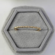 Gold full eternity bead ring displayed in a gray hexagonal recyclable kraft ring box, band width approx. 1.5mm