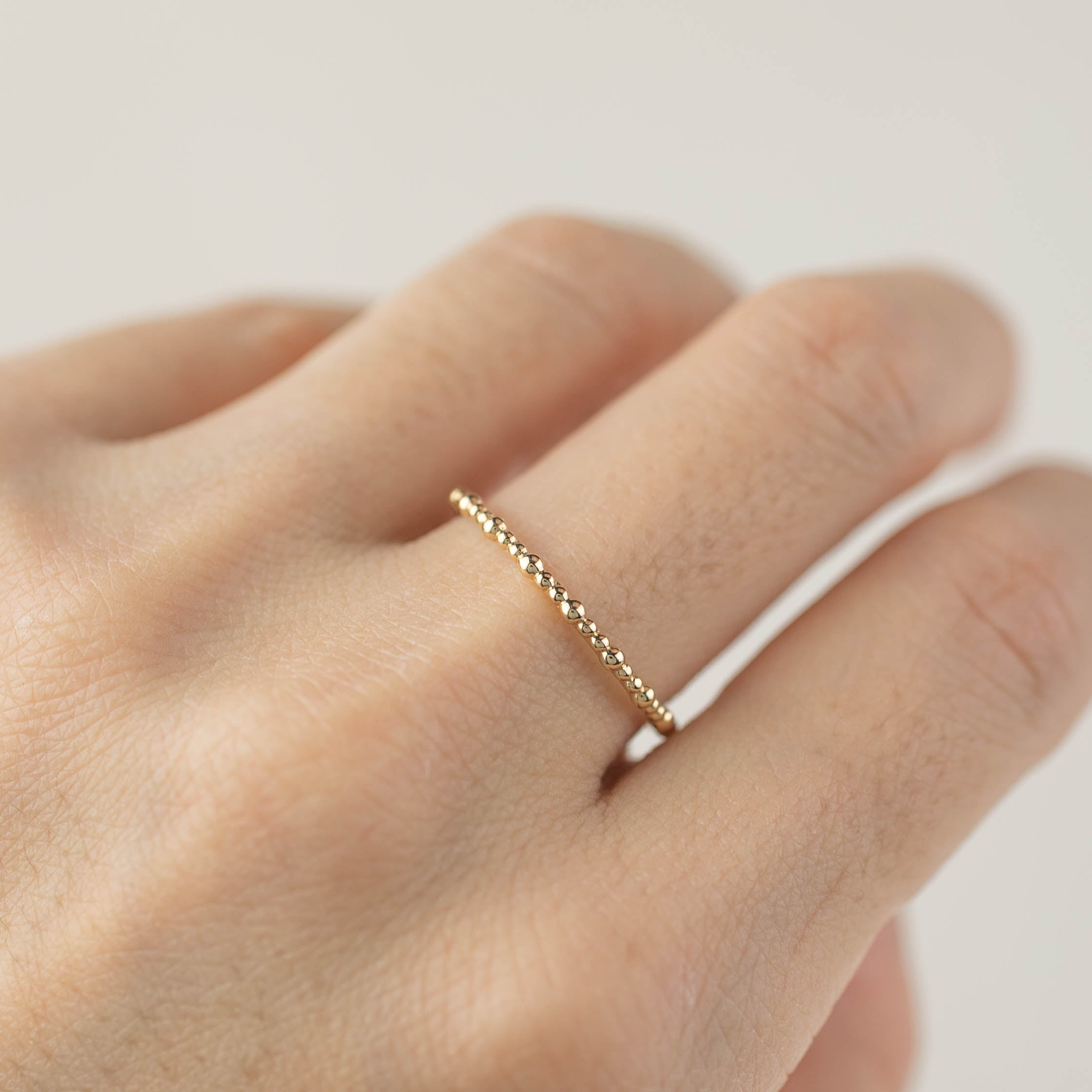 Close-up of a hand wearing a delicate full eternity style Gemma Ring made of ethically sourced solid gold