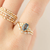 Close-up of Norah Tiara Ring with oval blue gemstone and white diamonds on gold band worn on finger