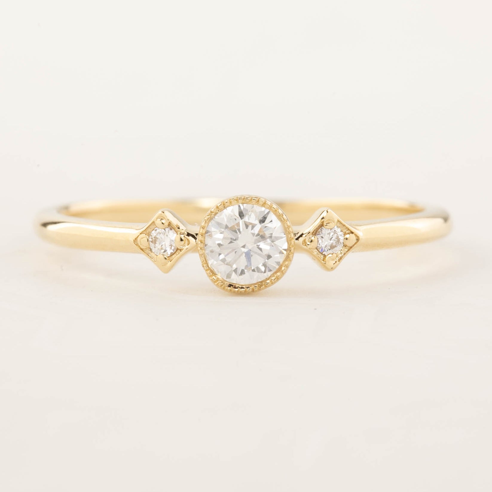 Gold moon and star ring with brilliant cut center diamond and two smaller accent diamonds in milgrain bezel setting