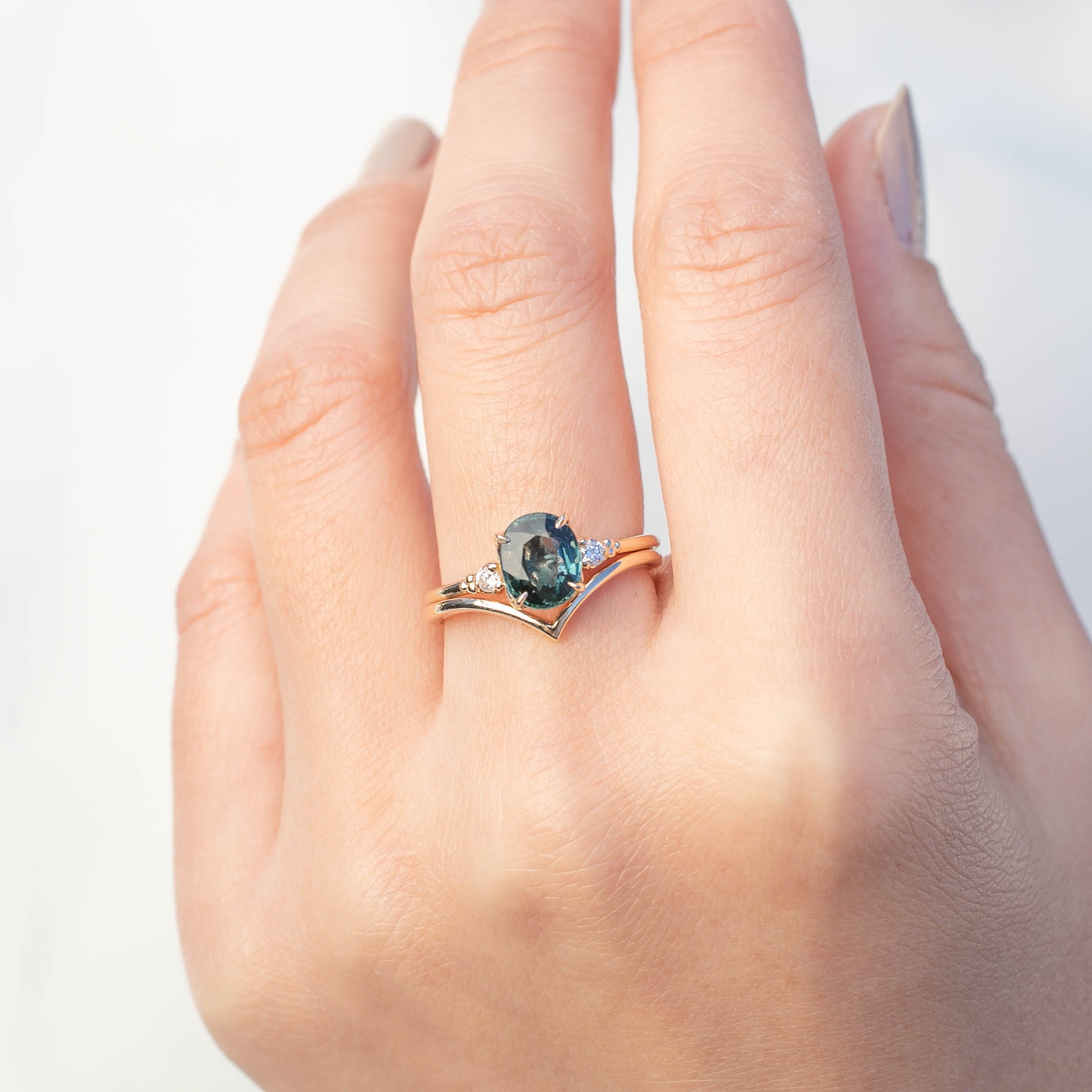 Close-up of a hand wearing an Ivy Ring with a dark gemstone on an ethically sourced solid gold band.