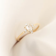 Oval rose cut diamond ring with white accent diamonds on slim gold band displayed on soft fabric