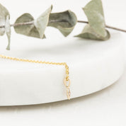 Close-up of a delicate 14k gold star charm with a 1.5mm bezel set birthstone on a fine chain.