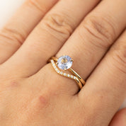Close-up of a hand wearing the Esperanza Ring with a white diamond and gold band on a light background