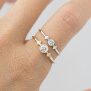 Close-up of two Moon & Star rings with brilliant-cut diamonds in gold and silver milgrain bezel settings on finger