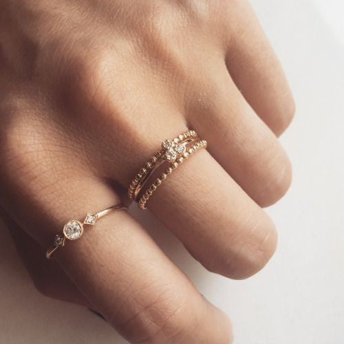 Close-up of hand wearing Dahlia Trio Diamond Ring with three delicate stacked gold bands and white diamonds