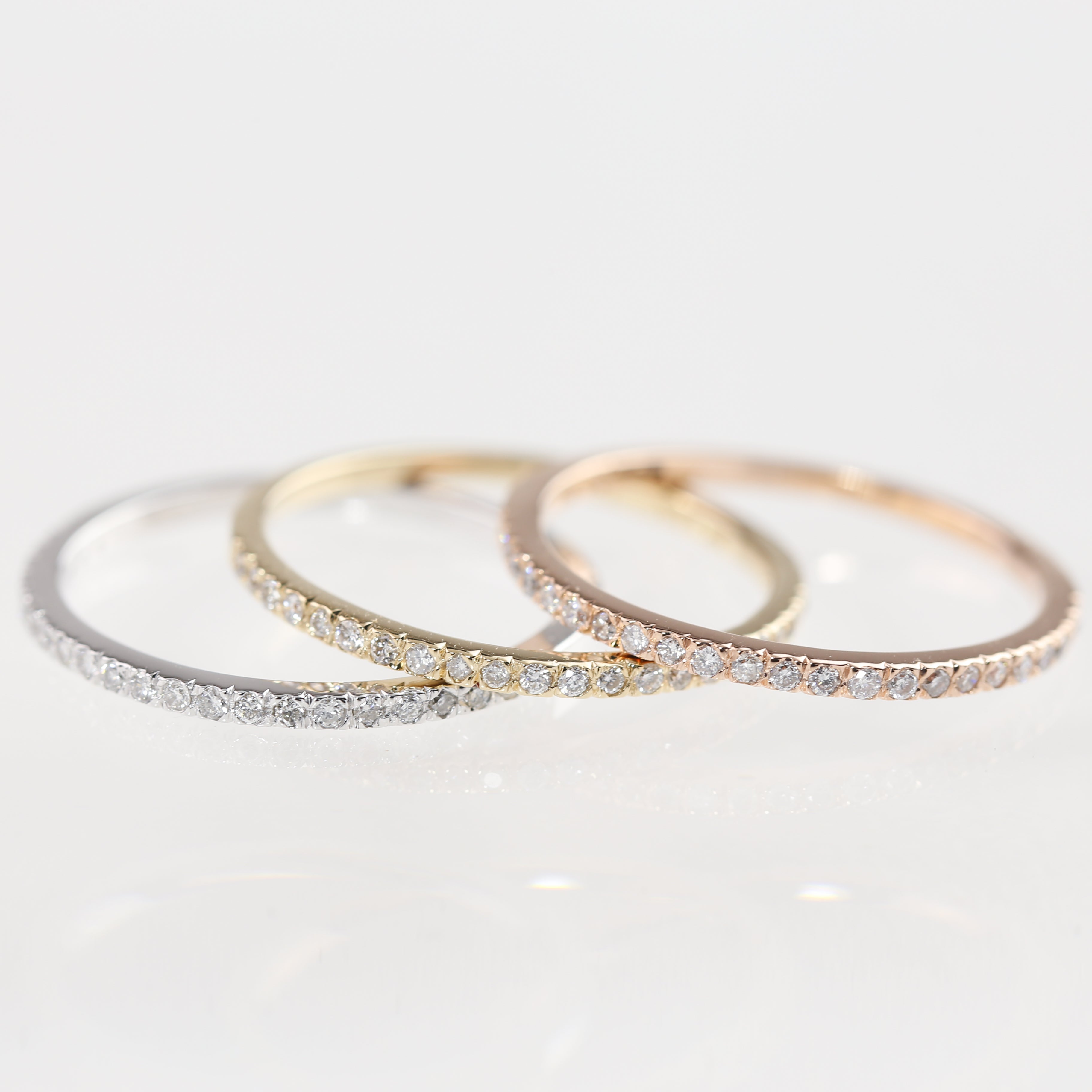 Three slim Meteor Diamond Bands in white, yellow, and rose gold, each with natural white diamonds set around the band