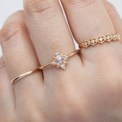 Close-up of a hand wearing a delicate gold Victoria Ring with a 0.41ct oval rose cut diamond and white accent diamonds
