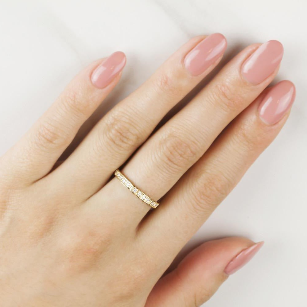 Hand wearing Eva ring with half-eternity natural white diamonds set in solid gold band, polished nails visible.