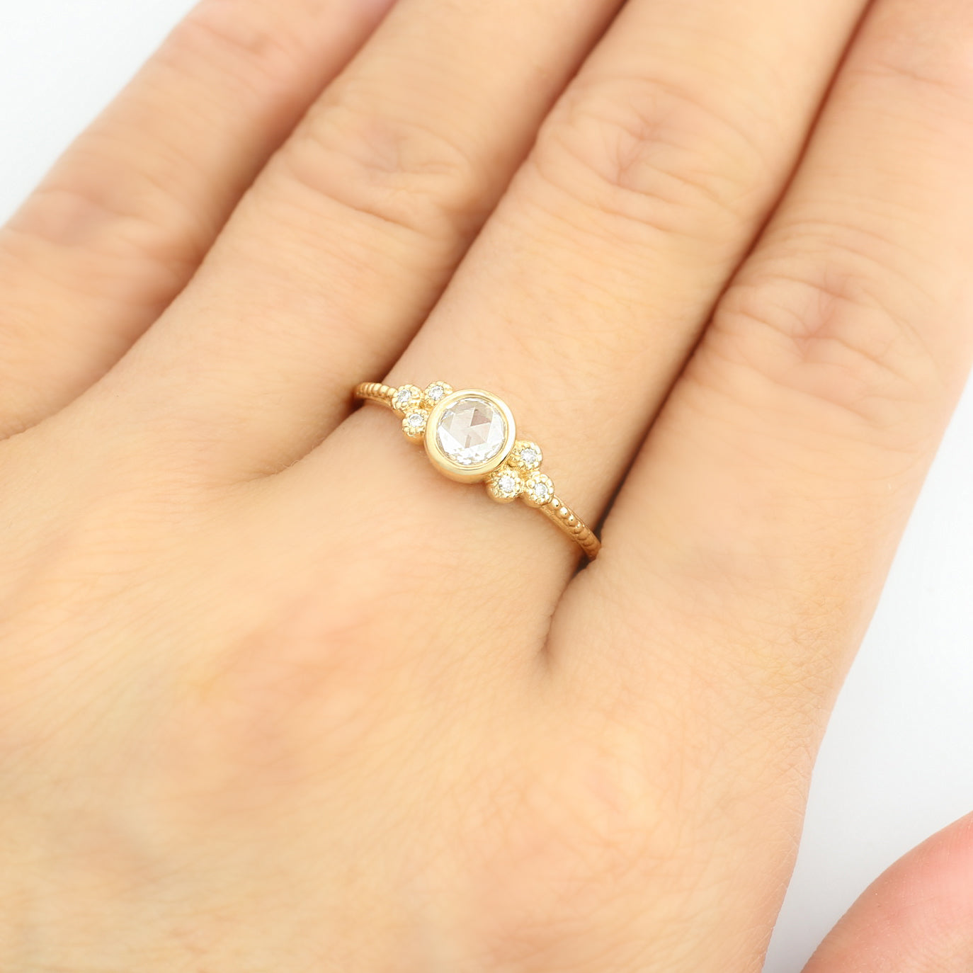 Faye Ring with 4mm rose cut diamond and six small diamonds on 14k yellow gold band on hand.
