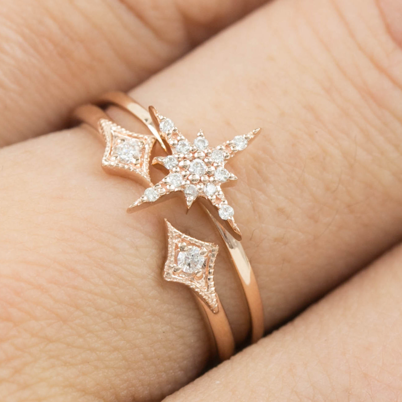 Rose gold starburst diamond ring with pave diamonds on a delicate 14k gold band worn on finger