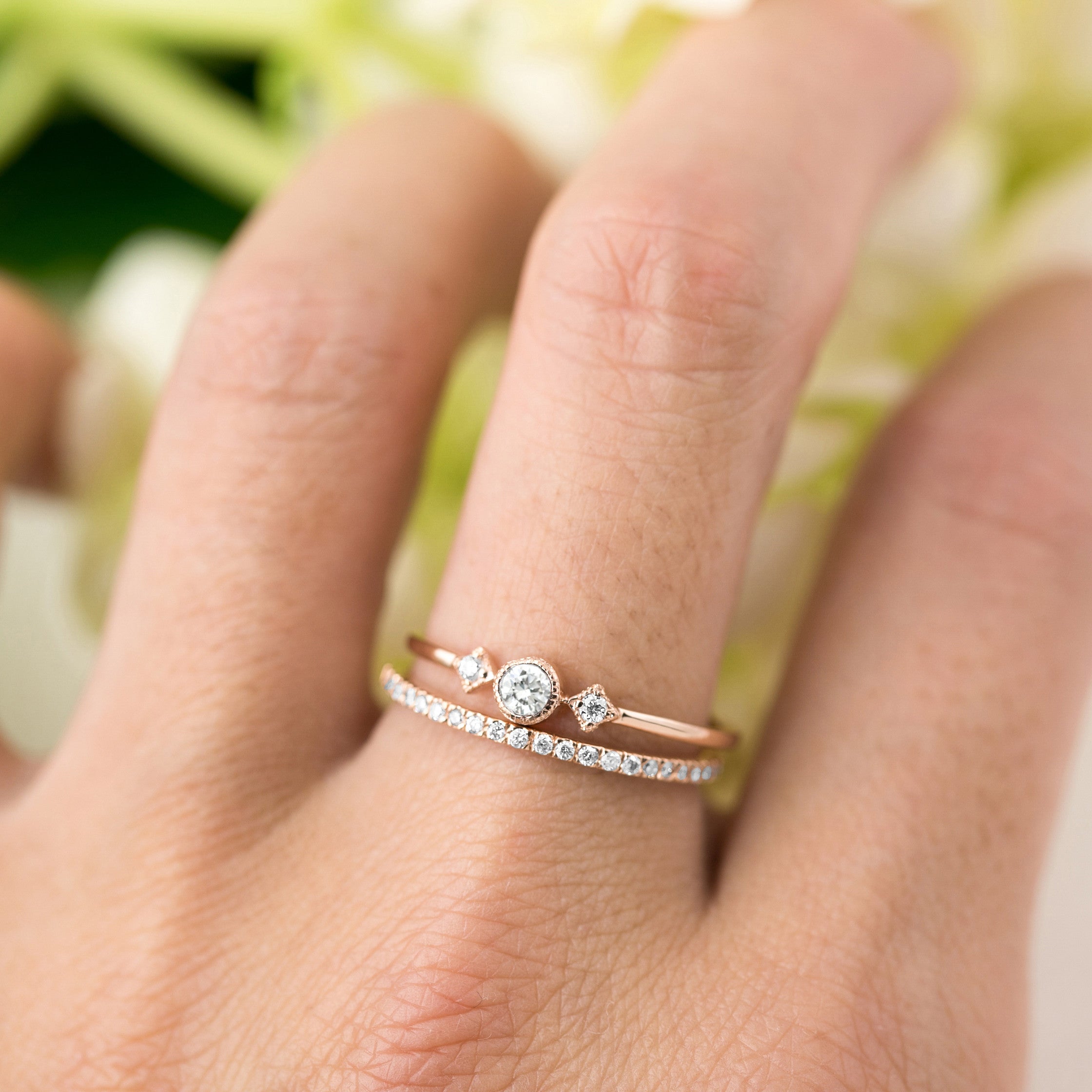 Close-up of a hand wearing a Meteor Diamond Band 1.3mm with natural white diamonds in rose gold.
